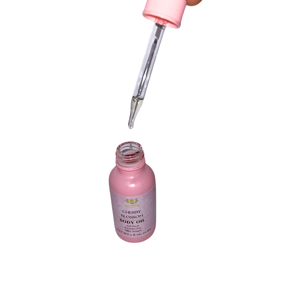 Pink bottle of body oil with a dropper on a white background